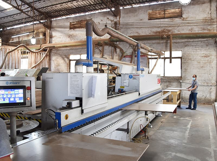 A worker monitoring and operating a large - scale automated machine in a factory workshop.