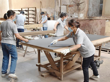 A worker processing wooden components with tools, focusing on precision.