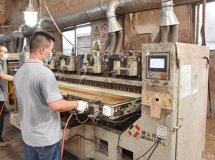 A worker operating large machinery to precisely cut or shape wood for customized products.