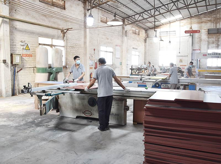 Workers operating machinery in a well - lit factory workshop.