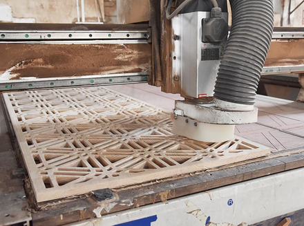 A worker handling wooden components on a machine, ensuring precision in the process.