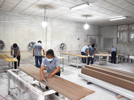 Workers are cutting and sanding wooden pieces in a clean and orderly workshop, demonstrating proficient skills.