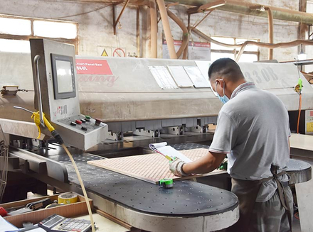 A worker handling metal components on a large machine, focusing on precision machining.