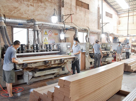 Workers and machinery in a workshop processing wood for customized orders.