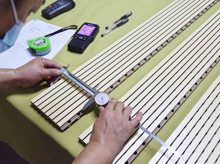 A worker measuring long - shaped components with precision tools to ensure accurate dimensions.