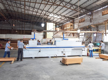 Several large machines and workers in a well - lit and ventilated factory workshop.